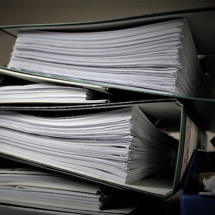 a pile of papers in 3 ringed binders